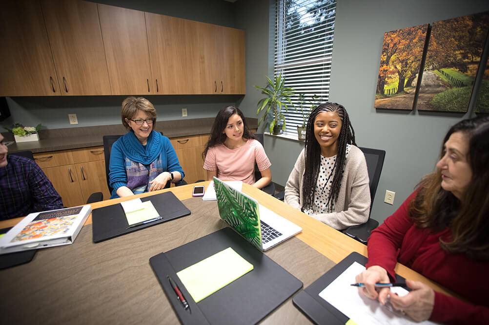 Students and professors sitting around a conference table