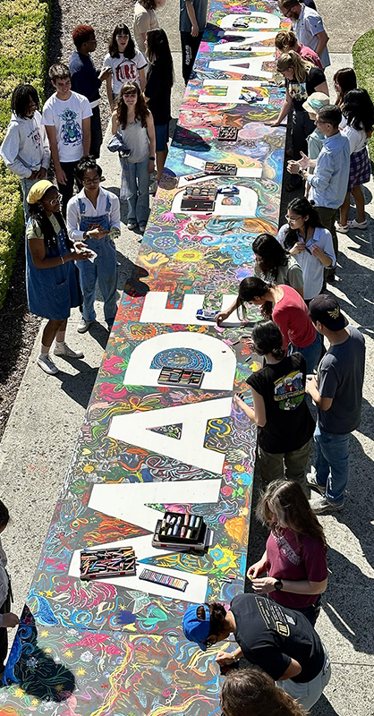 Students get together to make a large art pieced titled "Made by Hand"