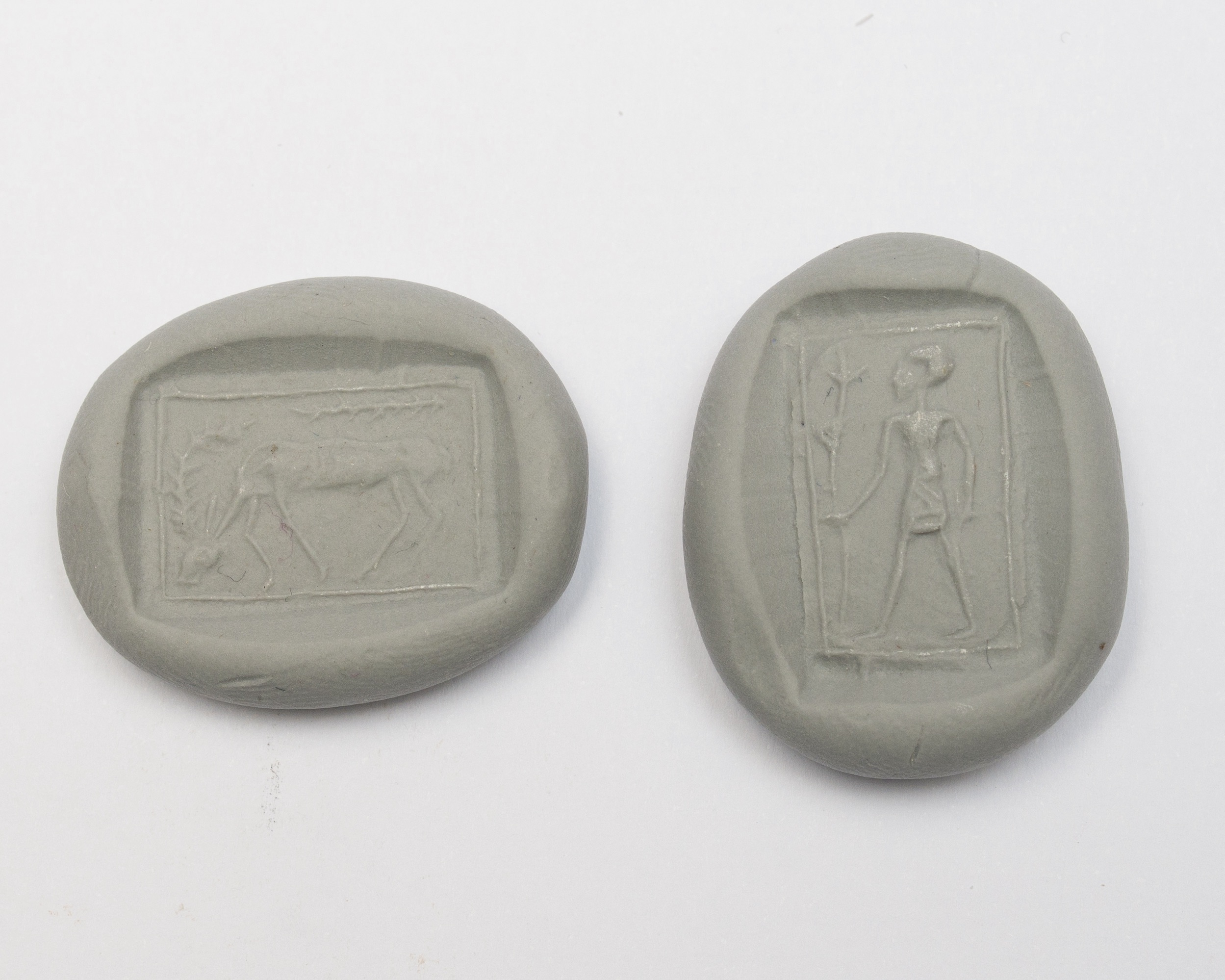 a seal impression set in two pieces of clay, one featuring a grazing animal and the other featuring a man holding a spear