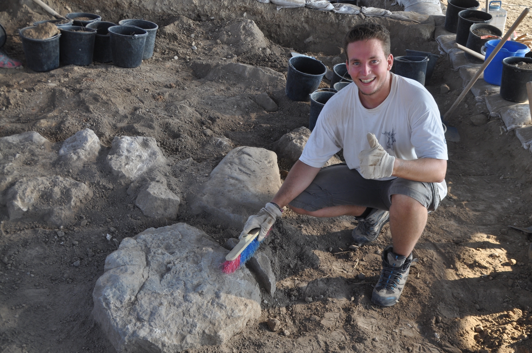 someone smiling by a big rock