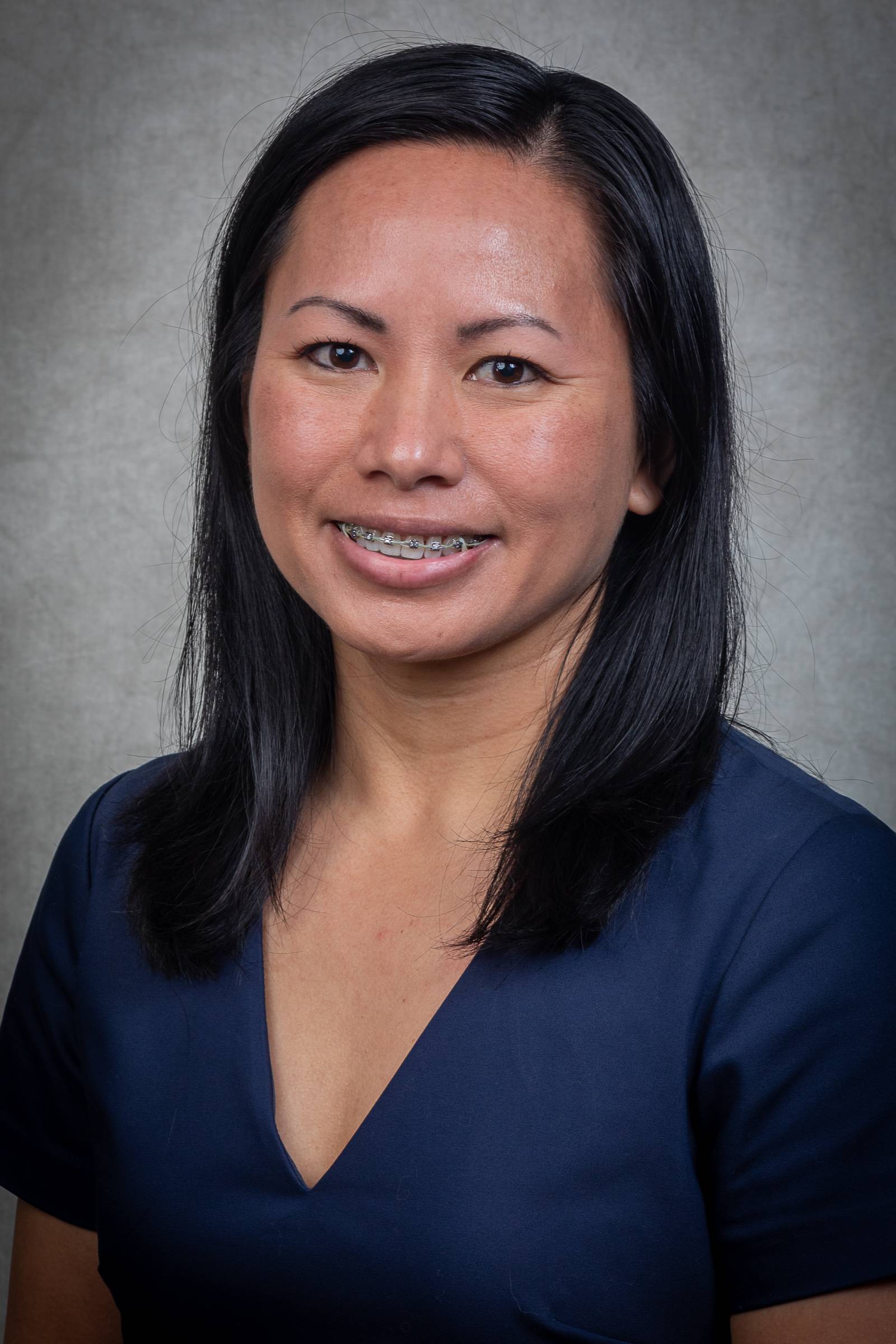 An professional portrait of Loni wearing a blue shirt with a light grey background. 