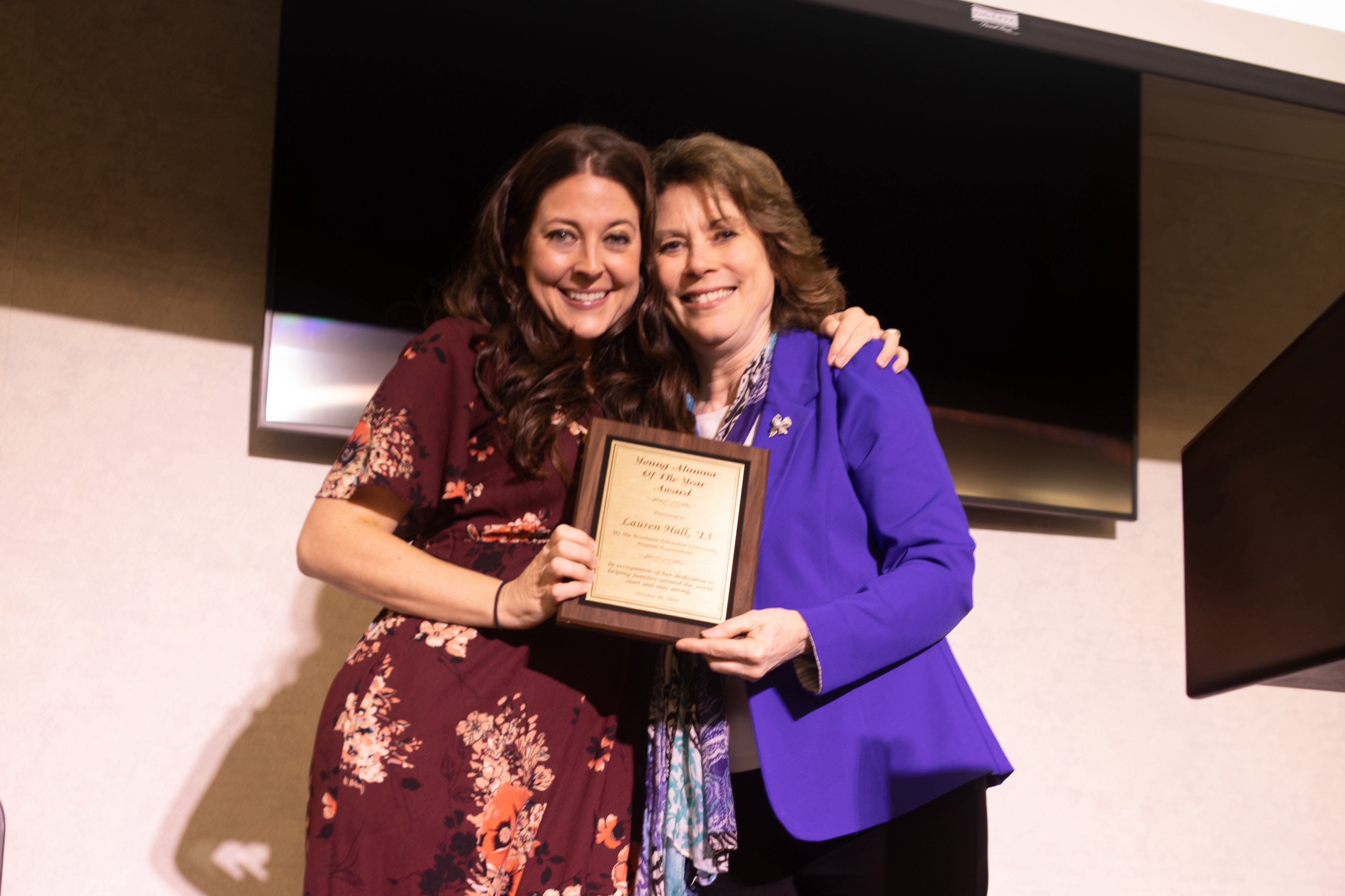 two people smiling with an award