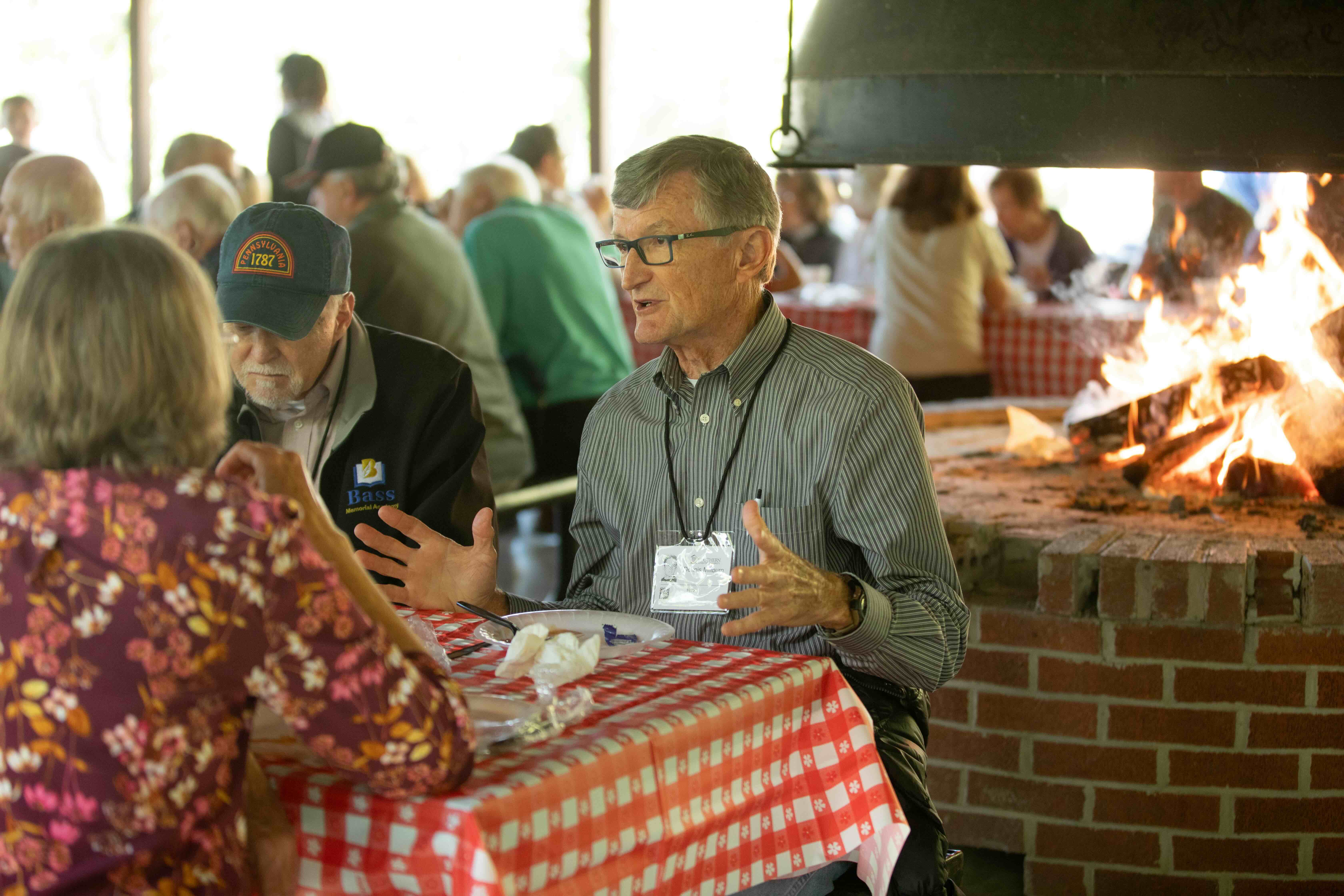 Homecoming Weekend Photo of 3 alumni eating lunch together at a picnic table