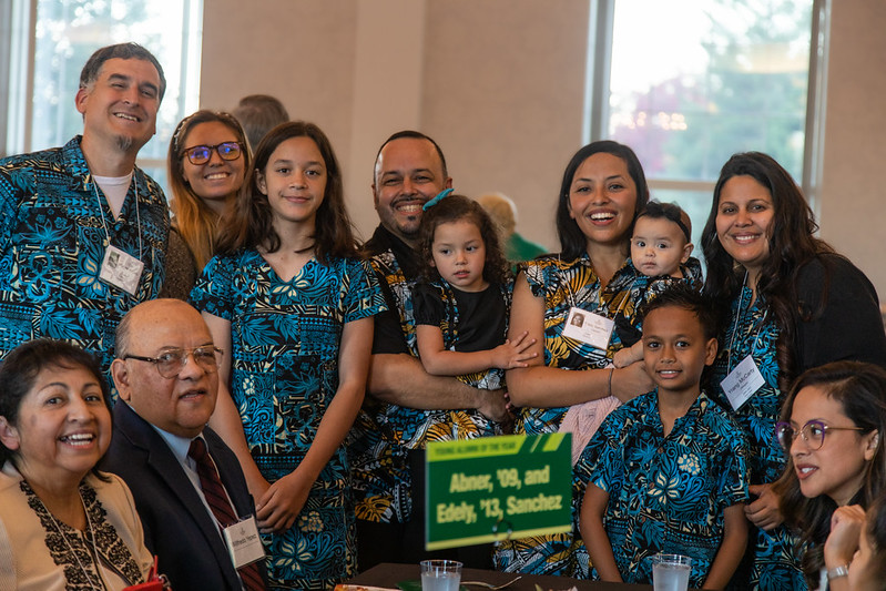 A picture of a family wearing matching blue shirts smiling at the camera.