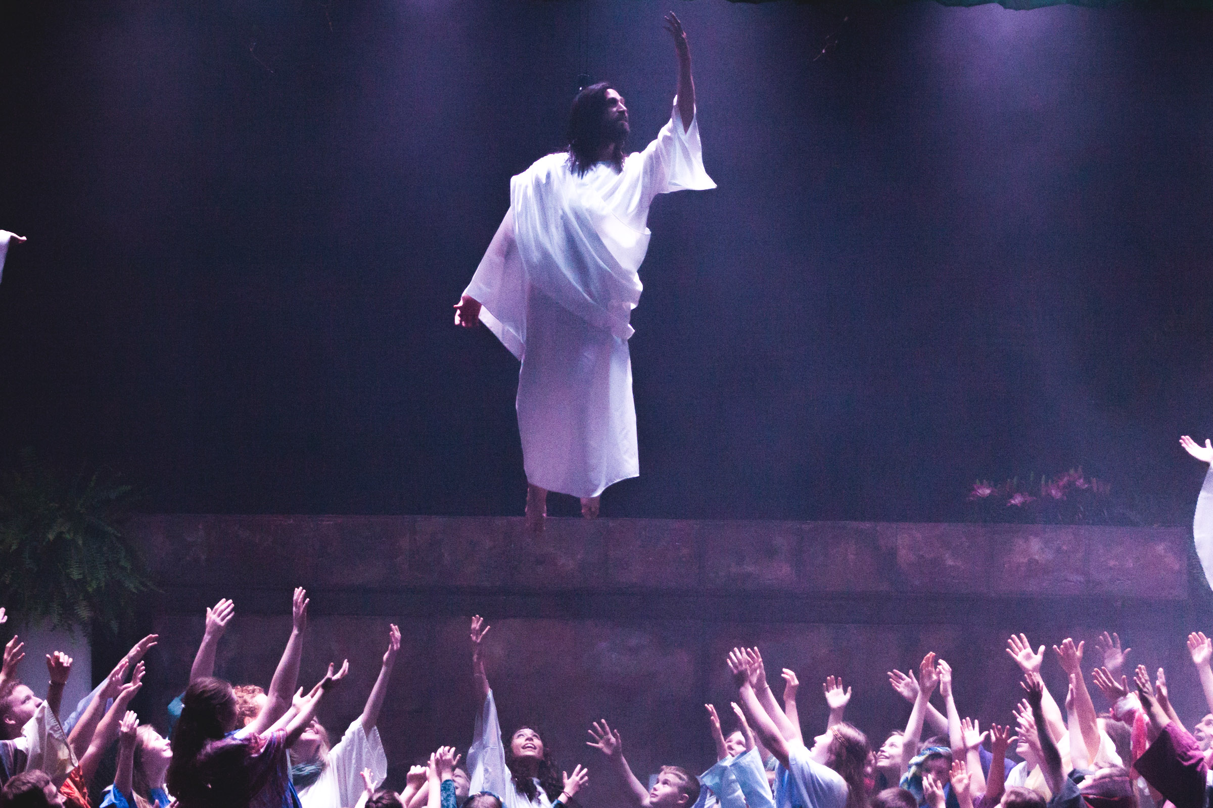 Jesus is lifted off the stage as believers raise their hands