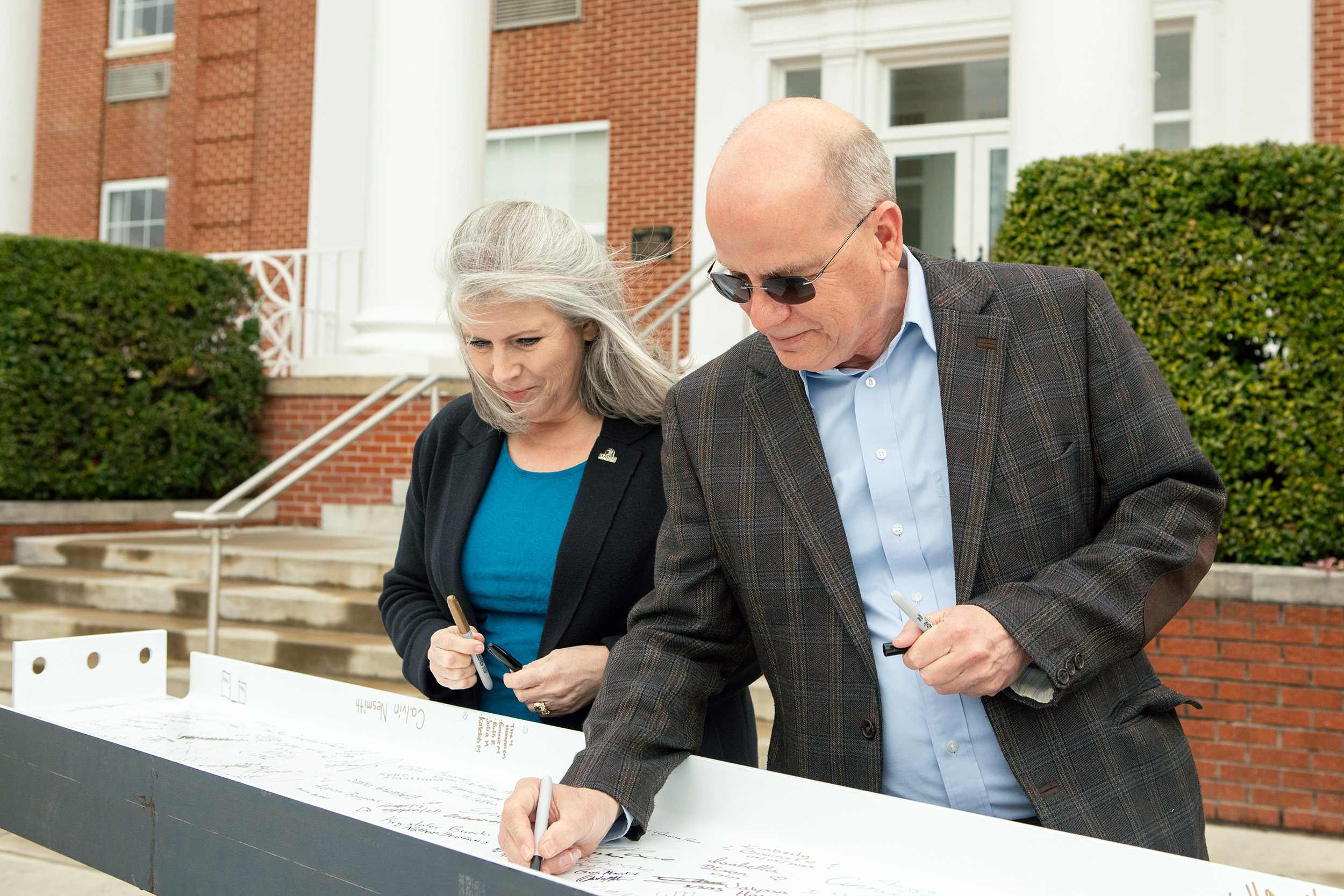 Ken Shaw, president, and Stephanie Sheehan, dean of the School of Business, sign the steel beam.